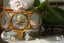 A collection of vintage gold rings displayed on a marble surface. One of them features a trio of yellow diamonds amongst white diamonds and reclaimed, hand-carved 18 karat gold. The rings are placed near a glass and gold metal trinket box.