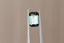 A natural emerald cut teal green sapphire available to add as a center stone for your heirloom ring setting at The North Way Studio. This stone has north and south poles of medium blue with the middle portion leaning more teal blue in its facets. The sapphire is shown facing the viewer and held with tweezers, a light reflection shining off of the face of the stone.