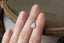 A natural egg-shaped pale mint and white sapphire available as a center stone for your heirloom setting at The North Way Studio. A soft pale mint, nearly silvery white in an elongated egg shape. The sapphire is shown resting on a woman's hand for size reference.