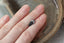 A natural elongated shield cut medium blue sapphire available to add as a center stone for your heirloom setting at The North Way Studio. Medium steely blue with notes of faint teal at tips. The sapphire is shown resting on a woman's fingers for size reference.