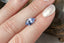 A periwinkle blue shield cut sapphire with light blue zoning shown on a hand