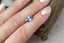 A periwinkle blue shield cut sapphire with light blue zoning shown on a hand
