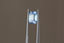 A glowing, faintly opalescent shade of light to medium blue emerald cut sapphire. This Sri Lankan sapphire is available for purchase alongside an heirloom setting at The North Way Studio. The sapphire is shown held up by tweezers.