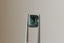 A natural emerald cut teal sapphire available to add as a center stone for your heirloom setting at The North Way Studio. A deeper forest teal hue. The sapphire is shown held up with tweezers.