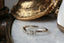 Reverie Diadem band by The North Way Studio featuring a crown of curved baroque leaves unfurling into a thin taper, encrusted with six petite white diamonds. Crafted in your choice of reclaimed 14 or 18 karat gold, this ring evokes the elegance of bygone eras with a delicate 'V' contour design. Shown facing left.