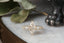 Fantasy elven alternative engagement ring designed by The North Way Studio. This custom three stone engagement ring is shown in reclaimed yellow gold with a warm-toned marquise diamond center. This fairytale inspired heirloom ring design features hand-carved gold leaves, two natural pear cut diamonds, and a cluster of diamond dewdrops.