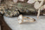 Fantasy elven alternative engagement ring designed by The North Way Studio. This custom three stone engagement ring is shown in 14 karat yellow gold with an oval diamond center. This fairytale inspired design features hand-carved gold leaves, two natural pear cut diamonds, and a cluster of diamond dewdrops.