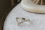 A dramatically tapered ring with leaves and a rustic carved band is topped with a pear cut diamond. Designed by The North Way Studio and shown here in white gold.
