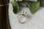 An antique inspired flower diamond halo engagement ring. This fairy garden engagement ring features a large natural gray diamond center with a diamond halo and hand-carved leaf and bark texture in 18 karat white gold. Ready to ship engagement ring crafted by The North Way Studio in collaboration with Claire Pettibone. Viewed from above.