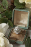 A flower engagement ring featuring a large natural gray diamond center with a diamond halo in an antique ring box.