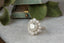 An antique inspired flower engagement ring featuring a large natural gray diamond center with a diamond halo and hand-carved leaf and bark texture in 18 karat white gold.