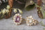 Two variations of the Peony heirloom engagement ring setting by The North Way Studio and Claire Pettibone are shown resting on a marble surface.