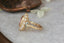 A flower engagement ring featuring a large natural pink spinel, diamond halo, marquise sapphire leaves, and hand carved leaves and bark texture in 18 karat yellow gold. An antique inspired fairy garden engagement ring. Ready to ship, crafted by The North Way Studio in collaboration with Claire Pettibone.