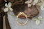 A flower engagement ring in natural pink spinel with diamond halo and sapphire leaves, hand carved leaves and bark texture in 18 karat yellow gold.