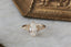 This custom heirloom engagement ring setting designed and crafted by The North Way Studio features delicate leaves carved in reclaimed gold and a cluster of diamond dew drops spun about your choice of center gemstone. This fantasy ring is shown in 14 karat yellow gold with a large pear cut diamond center.