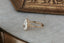 This custom fantasy engagement ring setting designed and crafted by The North Way Studio features delicate leaves carved in reclaimed gold and a cluster of diamond dew drops spun about your choice of center gemstone. This fairytale nature inspired ring is shown in 14 karat yellow gold with a large pear cut diamond center.