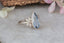 A multi stone engagement ring born of fairytales and enchanted gardens. This ethereal ring features a large blue pear cut sapphire, marquise natural diamond wings, and a soft bark texture carved into 18 karat white gold. This romantic fantasy inspired ring is ready to ship, size 6 1/2. Crafted by The North Way Studio in collaboration with Claire Pettibone.