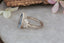 A multi stone engagement ring born of fairytales and enchanted gardens. This ethereal ring features a large blue pear cut sapphire, marquise natural diamond wings, and a soft bark texture carved into 18 karat white gold. This romantic fantasy inspired ring is ready to ship, size 6 1/2. Crafted by The North Way Studio in collaboration with Claire Pettibone.