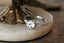 Marquise diamonds and unfurling carved gold leaves nestle a uniquely chosen center stone in this heirloom engagement ring setting designed and crafted by The North Way Studio. This ethereal three stone engagement ring is shown cast in 14 karat white gold with an old European cut white sapphire center and is viewed close up resting on an antique trinket.