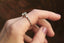 Marquise diamonds and unfurling carved gold leaves nestle a uniquely chosen center stone in this heirloom three stone engagement ring setting designed and crafted by The North Way Studio. This ethereal fantasy engagement ring is shown cast in 14 karat white gold with an old European cut white sapphire center and worn on the index finger of a left hand.