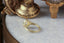 An elven fairytale alternative engagement ring crafted by The North Way Studio. This gothic architecture fantasy inspired solitaire ring features hand-carved leaf details, claw prongs, and a custom center stone. The customizable ring is shown in reclaimed yellow gold and lab grown oval diamond and is facing away to the left, with focus on the hand-carved gold.