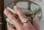 A timeless fairytale alternative engagement ring crafted by The North Way Studio. This fantasy inspired solitaire ring features hand-carved leaf details, claw prongs, and a custom center stone. The customizable ring is shown in reclaimed yellow gold and lab grown oval diamond. Shown on a woman's hand.