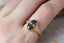 A timeless fairytale alternative engagement ring crafted by The North Way Studio. This fantasy inspired solitaire ring features hand-carved leaf details, claw prongs, and a custom center stone. The customizable ring is shown in reclaimed yellow gold and natural fancy gray oval diamond. This ring is ready to ship and is shown worn on the first finger of a woman's hand.