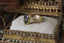 A timeless fairytale engagement ring crafted by The North Way Studio. This alternative fantasy inspired solitaire ring features hand-carved leaf details, claw prongs, and a custom center stone. This ready to ship ring is cast in reclaimed yellow gold and has a natural fancy dark gray diamond center.