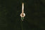A small gold charm with natural green tourmaline and hand-carved leaf details. Shown hanging on The Fae Hoop earring.