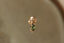 A small gold charm with natural green tourmaline and hand-carved leaf details designed to hang on The Fae Hoop earrings. Shown in yellow gold.