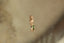 A profile view of a small gold charm with natural green tourmaline and hand-carved leaf details.