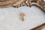 A small gold charm with natural green tourmaline and hand-carved leaf details.