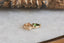 A small gold charm with natural green tourmaline and hand-carved leaf details.