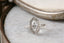 A solitaire fantasy engagement ring crafted by The North Way Studio. This fairytale ring features a lab grown marquise diamond, an engraved shield setting, and organic carvings in the gold on one side. Shown in 14 karat white gold.