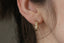 Everyday solid gold hoop earrings shown on the ear with hand-carved Indigo flowers.
