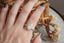 A nature inspired leaf prong and diamond halo engagement ring in lab grown oval diamond and yellow gold