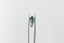 A natural elongated shield cut medium blue sapphire available to add as a center stone for your heirloom setting at The North Way Studio. Medium steely blue with notes of faint teal at tips. The sapphire is shown held up by tweezers.