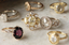 A collection of antique engagement rings lie on top of a marble surface. They are mix of white gold, yellow gold, and rose gold. They also feature various ring settings of white diamonds, yellow diamonds, and sapphires.