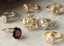 Alt Text: A collection of antique engagement rings lie on top of a marble surface. They are mix of white gold, yellow gold, and rose gold. They also feature various ring settings of white diamonds, yellow diamonds, and sapphires.