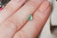 Opalescent teal lime green natural pear cut sapphire. This magical sapphire is available at The North Way Studio to be added to a custom heirloom setting. Shown resting on a woman's fingers for reference.