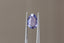 A uniquely shaped, lush portrait-cut sapphire in a regal purple hue. This sapphire is available for purchase alongside an heirloom setting at The North Way Studio. The sapphire is shown held up by tweezers.