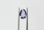 A uniquely shaped, lush portrait-cut sapphire in a regal purple hue. This sapphire is available for purchase alongside an heirloom setting at The North Way Studio. The sapphire is shown held up by tweezers on a white background.