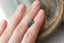 A natural elongated shield cut medium blue sapphire available to add as a center stone for your heirloom setting at The North Way Studio. Medium steely blue with notes of faint teal at tips. The sapphire is shown resting on a woman's fingers for size reference.