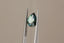 A natural pear cut blue green sapphire available to add as a center stone for your heirloom setting at The North Way Studio. A mesmerizing sapphire pool of greens and blues. The stone is shown held up by tweezers.