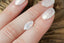 A large opalescent white marquise sapphire shown on a hand