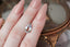 An ethereal blend of pale yellow and soft silvery blue hues in a modified pear cut sapphire.  This 2.59 carats Sri Lankan sapphire is available for purchase alongside an heirloom setting at The North Way Studio. The sapphire is shown resting on a woman's fingers atop an antique jewelry box for size reference.