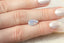 A large opalescent pale blue pear cut sapphire shown on a hand