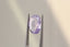 A natural oval light purple and pink sapphire available to add as a center stone for your heirloom ring setting at The North Way Studio. A lovely pale lilac pink with perhaps a hint of opalescence at some angles. The sapphire is shown held in tweezers tilted to the side.