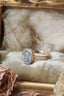 A blue sapphire ring designed and crafted by The North Way Studio in collaboration with Claire Pettibone and cast in reclaimed gold is shown atop an antique gold jewelry box.