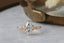 A customizable solitaire fantasy engagement ring setting with small brilliant cut diamonds set into leaf prongs. Shown in reclaimed 14 karat yellow gold with a lab grown marquise diamond. Elven fairytale engagement ring designed by The North Way Studio.